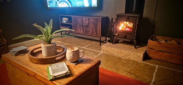 a cosy living room with a fire glowing in the log burner, a hot chocolate sits on the coffee table in foreground